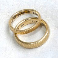 Handcrafted 14k yellow gold wedding rings with textured finish and engraving