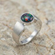 Handcrafted matte white gold ring with vivid black opal and modern architectural setting