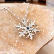 Handgefertigter Schneeflocken Anhänger aus Silber mit blauem Topas